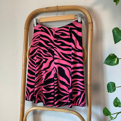 Pink and black zebra-striped skirt on a wooden tray with a white background