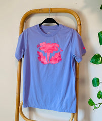 Purple t-shirt with pink graphic on a wooden chair against a light background